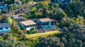 A large, two-story house with a spacious patio and a driveway leading to a gated entrance.