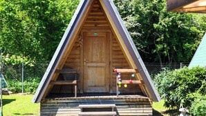 Une structure en bois en forme de toit à deux versants, avec une porte, un banc et des décorations colorées.