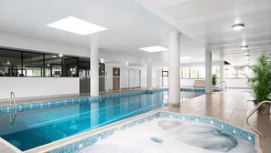 An indoor swimming pool with clear blue water, surrounded by white walls and columns, and equipped with a changing room and a sauna area. - Modern 3BR Apt w Parking near ICC & Darling Harbour (Ultimo)