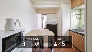 Una cocina compacta con microondas, hervidor y una pequeña mesa de comedor.