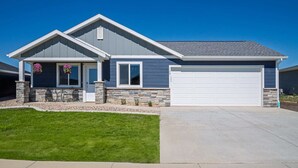 Une maison moderne à deux étages, avec des fondations en pierre, un garage et une pelouse bien entretenue.