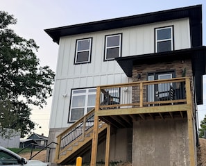 A two-story building with a wooden deck and a staircase leading to a balcony.