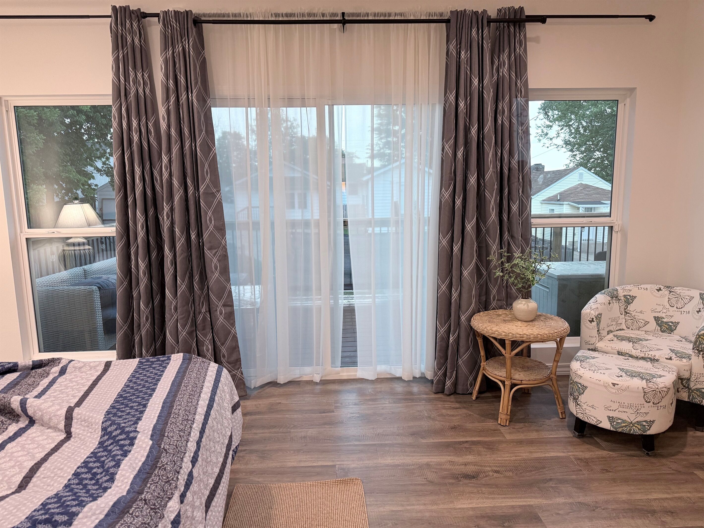 A bedroom with a bed, a chair, a small table, and a window with curtains.