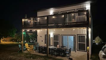 A two-story building with a balcony, outdoor seating area, and a car parked nearby.