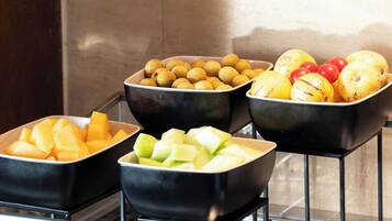 Three black bowls containing different fruits on a metal rack.