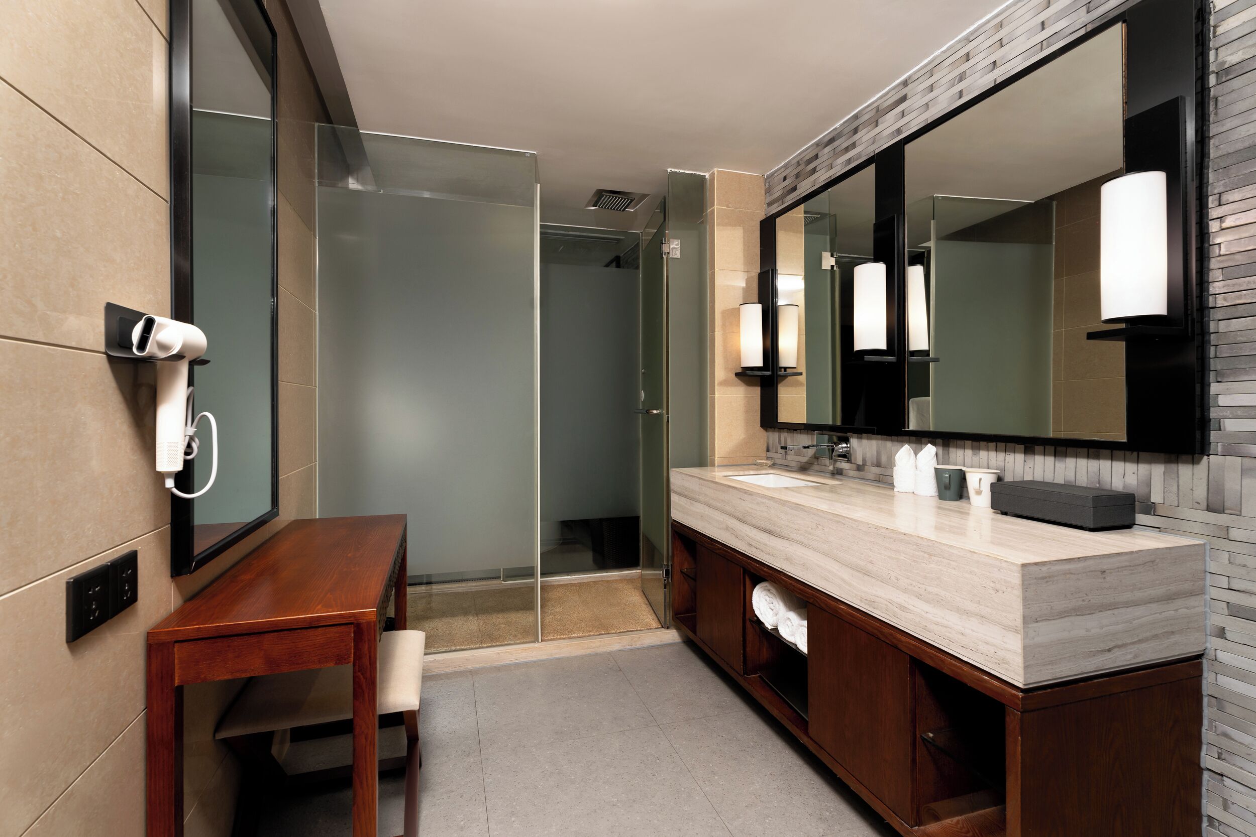 A modern bathroom with a wooden vanity, a large mirror, and a glass shower enclosure.