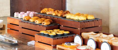 A buffet with various pastries and bread displayed on wooden stands.