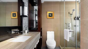 Un baño moderno con un mueble de tocador de madera, cabina de ducha de vidrio y dos cuadros en la pared.