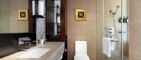 A modern bathroom with a wooden vanity, a glass shower enclosure, and two framed pictures on the wall.