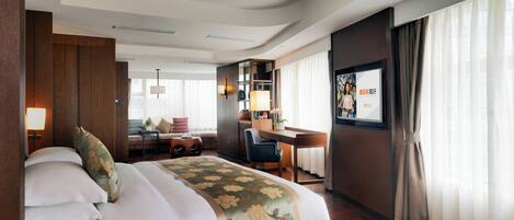 A hotel room with a bed, desk, chair, and a large window with curtains.