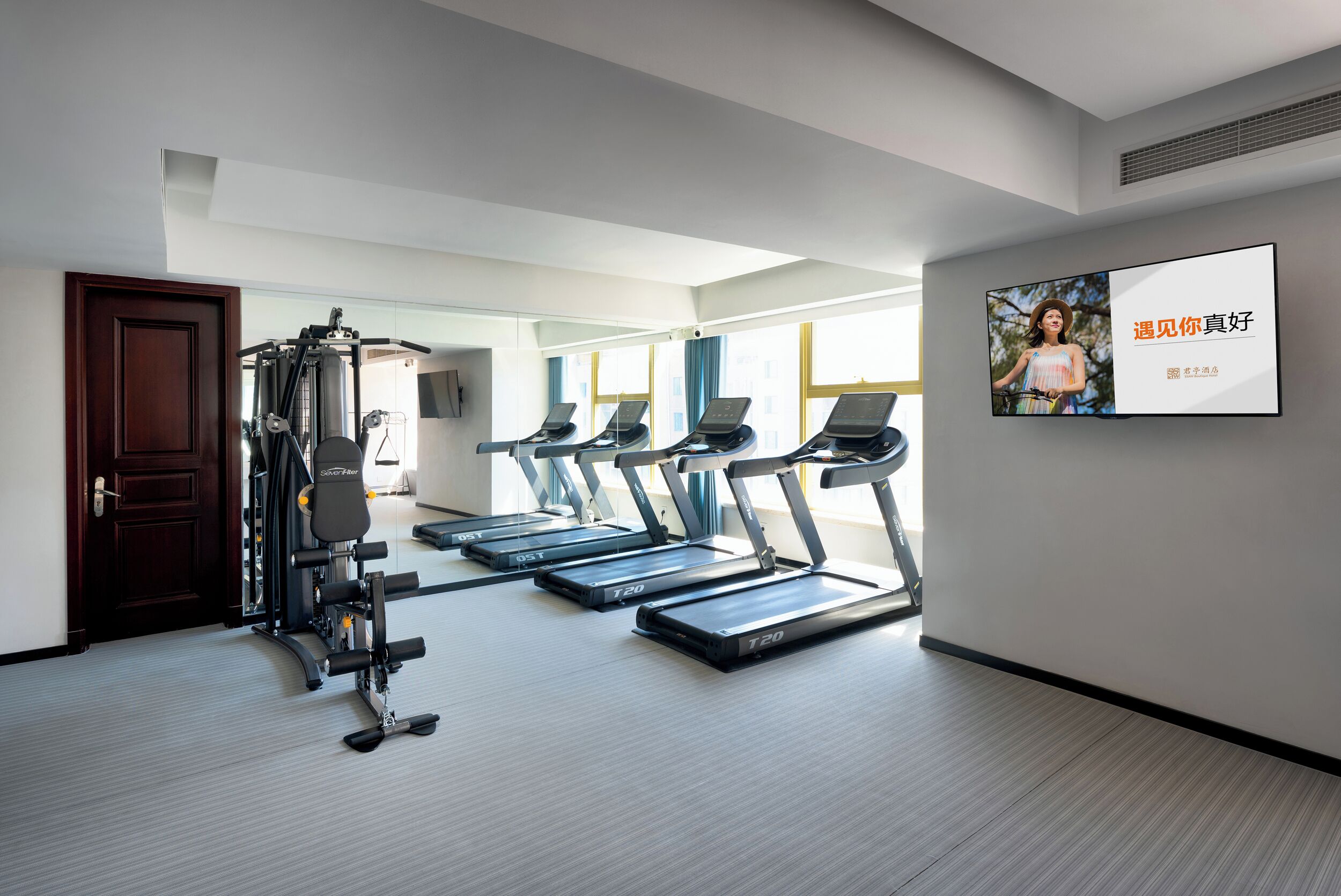 Et moderne fitnesscenter med løbebånd, styrkemaskiner og et stort spejl.