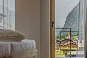A bed with a wooden headboard and a window view of a mountain and a church. - Chalet Waldhart in the middle of the Ötztal (Umhausen)