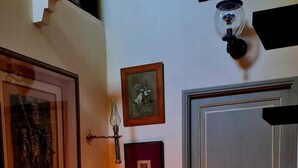 Un couloir avec une table sur laquelle repose un objet sphérique, une porte et des tableaux encadrés accrochés au mur.