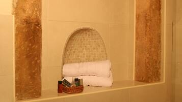 Un baño con pared de azulejos, un perchero y una cesta de artículos de aseo.