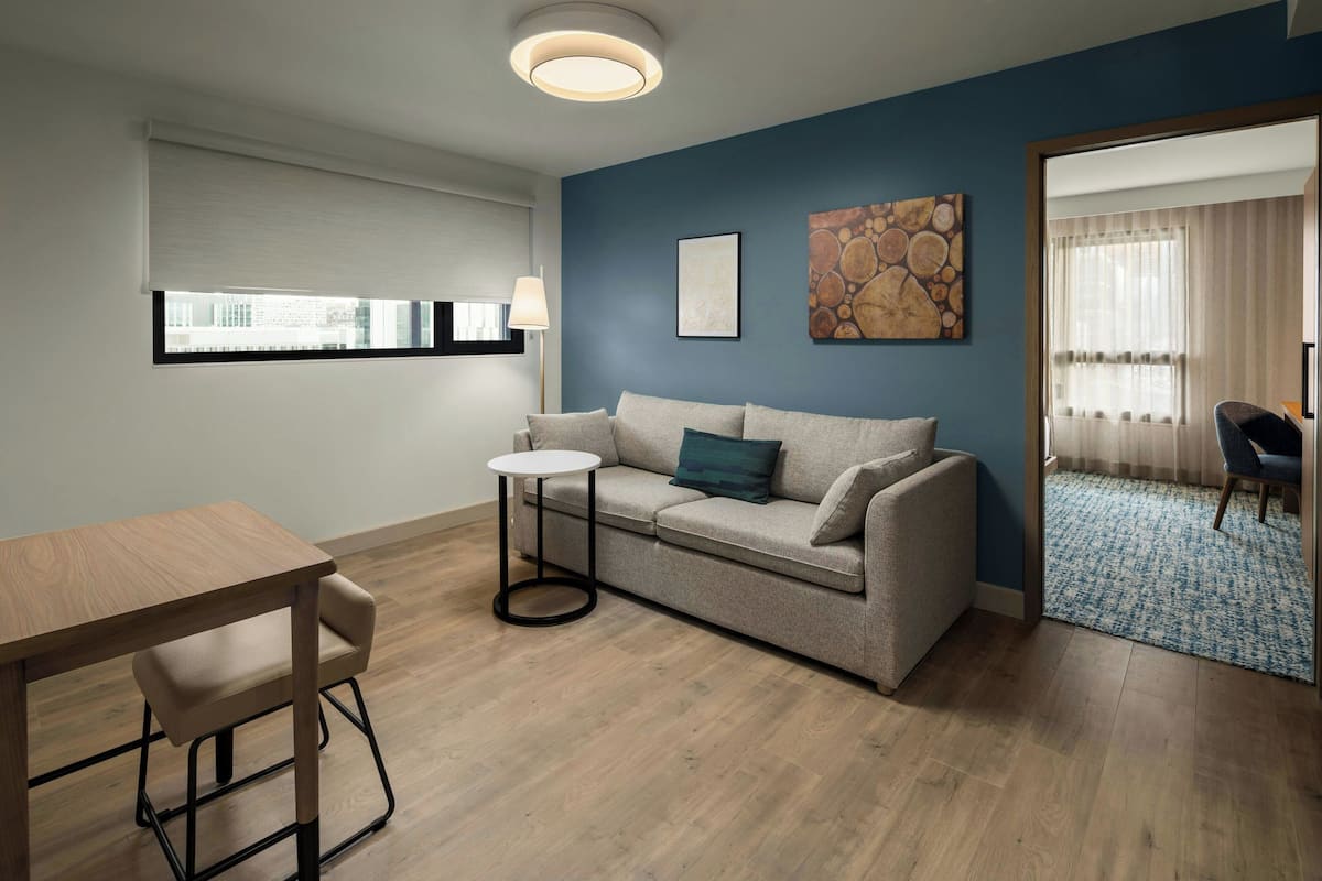 A modern living room with a sofa, a small round table, and a dining table.