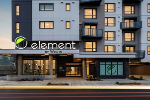 A modern hotel entrance with a glass facade, a logo above the name 'Element by Westin', and a well-lit entrance area.