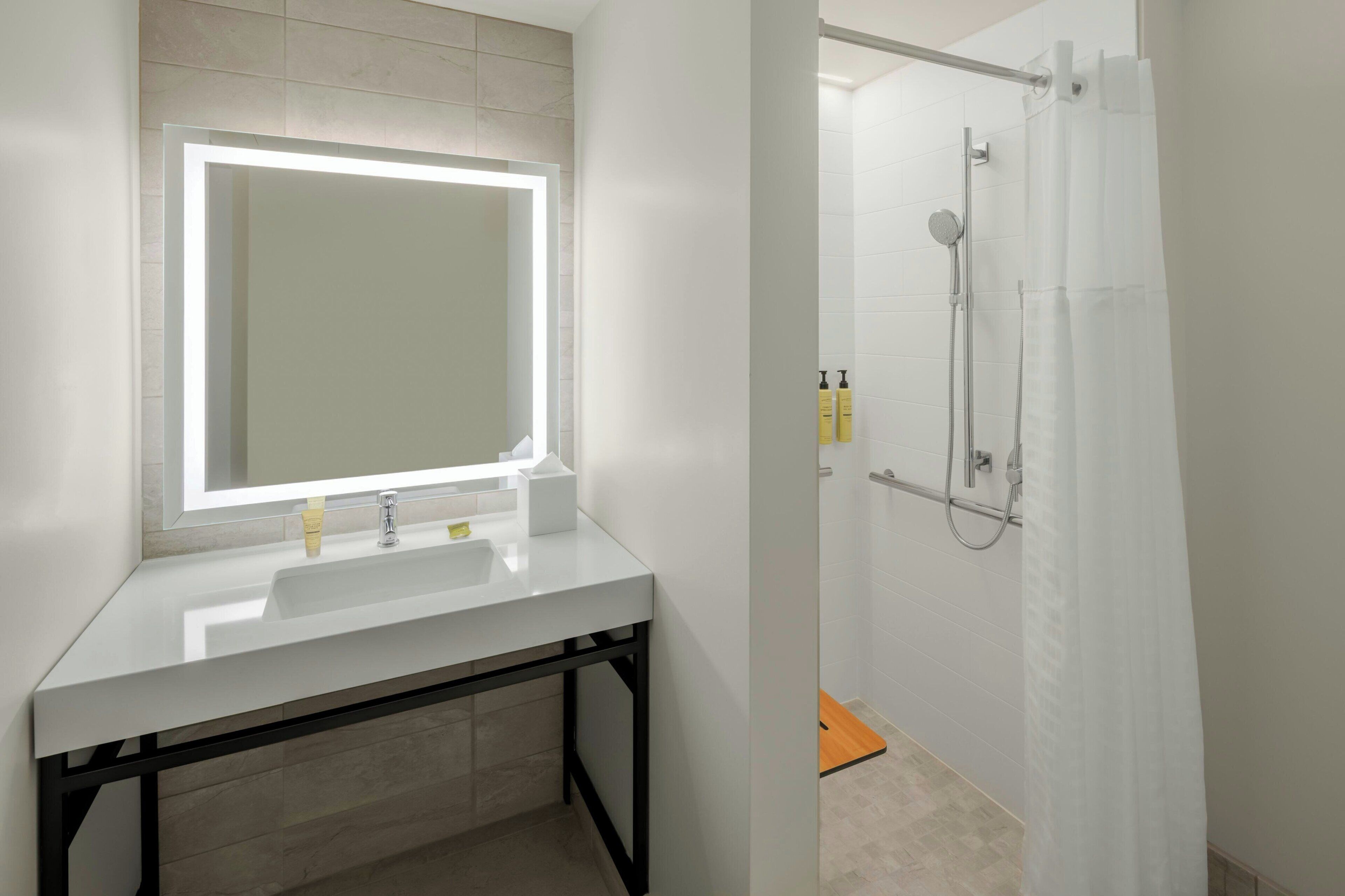 A modern bathroom with a white sink, mirror, and shower.