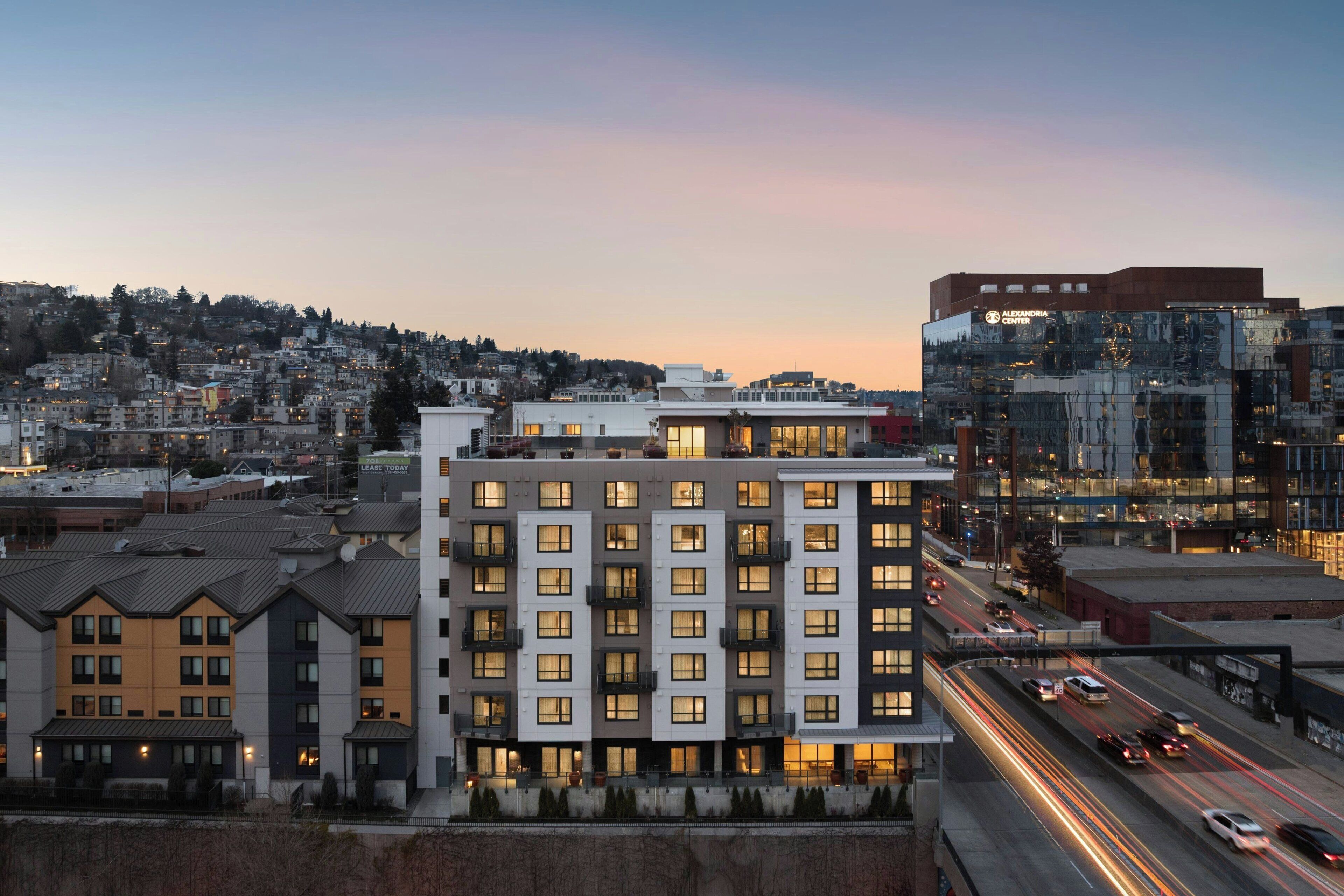 A multi-story hotel with a modern architectural design, featuring a prominent entrance and a view of the surrounding urban area.