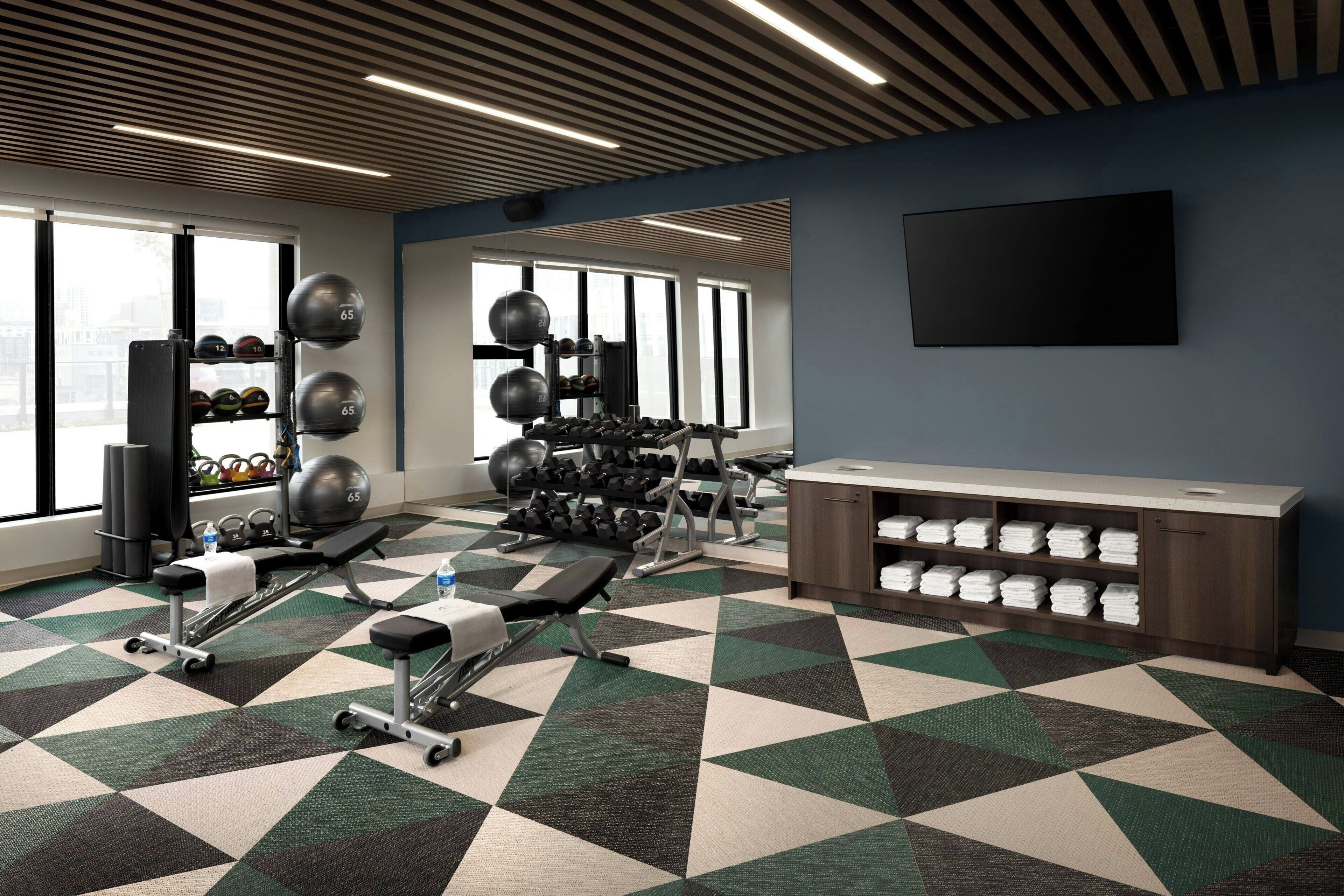 A gym with exercise equipment, a mirrored wall, and a TV.