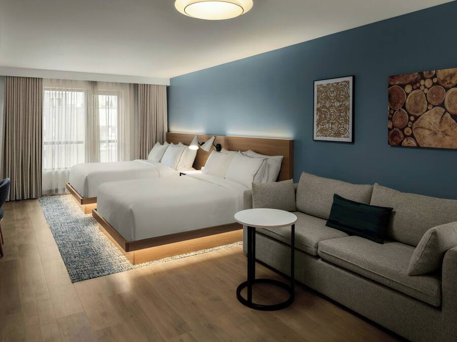 A hotel room with a large bed, a sofa, a small table, and artwork on the wall.