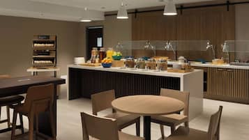 A modern breakfast area with a central island, seating, and a variety of food and drink options.