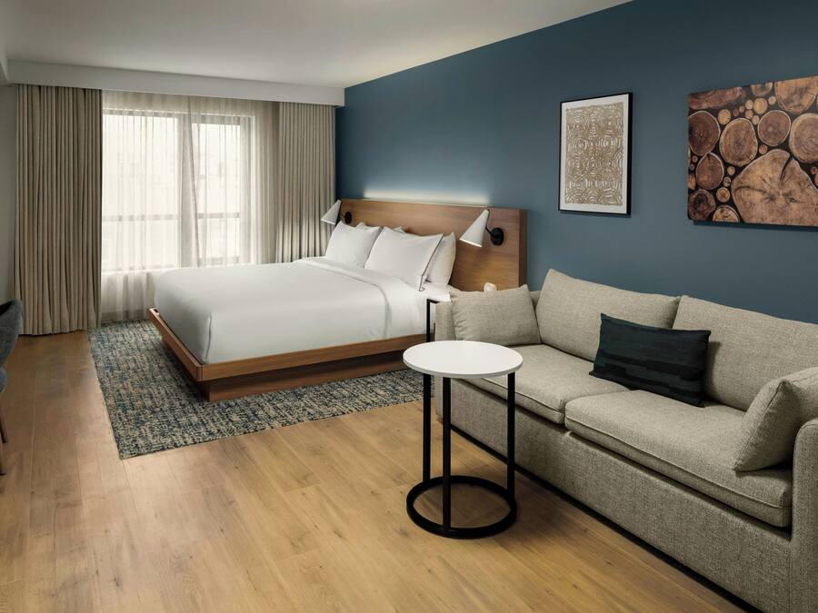 Habitación de hotel con cama, sofá, una mesita y obras de arte en las paredes.