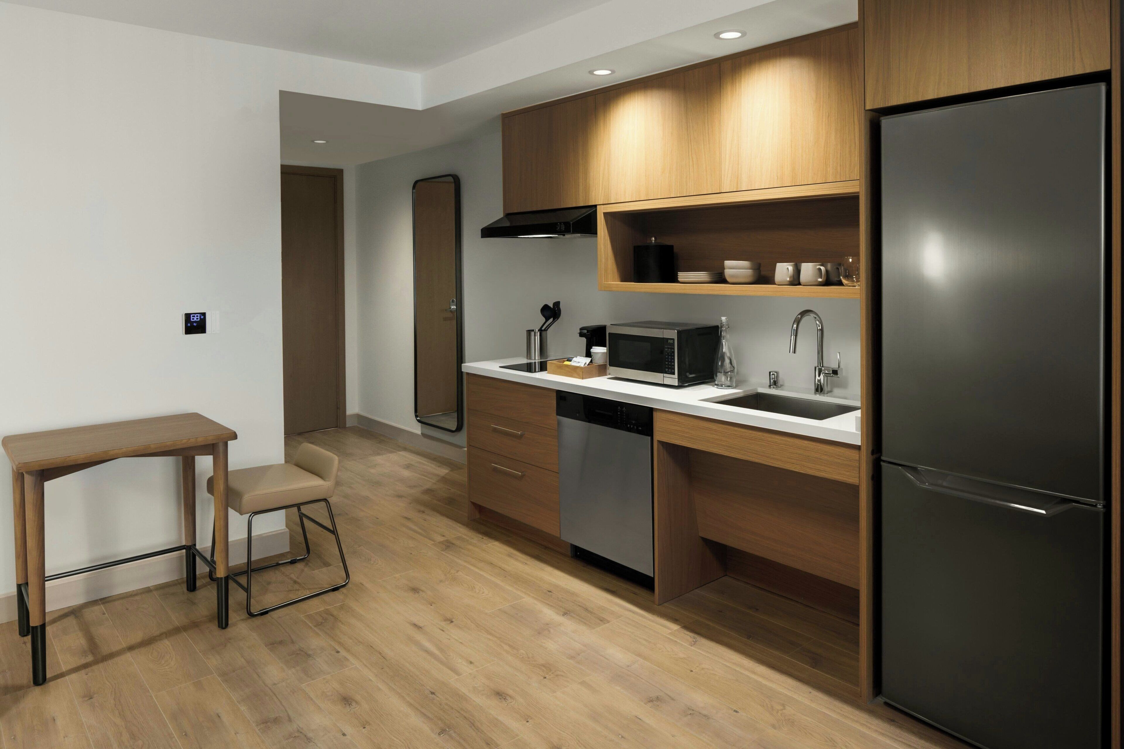 A modern kitchen with wooden cabinets, a stainless steel refrigerator, a microwave, and a dishwasher.
