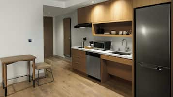 A modern kitchen with wooden cabinets, a stainless steel refrigerator, a microwave, and a dishwasher.