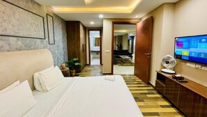 Une chambre d’hôtel avec un grand lit, une télévision, un ventilateur et une armoire en bois.