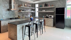 Une cuisine moderne dotée d’un îlot central, de tabourets de bar, d’un four à micro-ondes et d’un réfrigérateur noir.