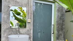 Une salle de bain avec un lavabo blanc, un miroir et une porte.