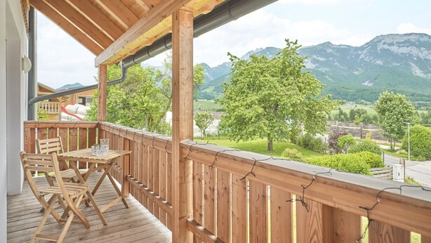 A wooden deck with a table and chairs, overlooking a mountainous landscape. - Getaway Apartment 8 Hauser Kaibling (Haus)