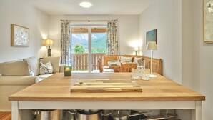 A modern kitchen with a wooden countertop, a dining area with a wooden table and chairs, and a balcony with a view of mountains. - Getaway Apartment 8 Hauser Kaibling (Haus)