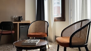 A hotel room with a view of a tower, two wicker chairs, a small table with a book, and a desk with two glasses and a coffee maker. - PALAZZETTO SAN MARCO (Venice)