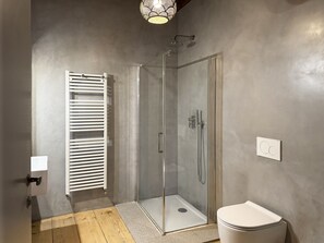 Un baño moderno con ducha de vidrio, inodoro blanco y perchero para toallas.