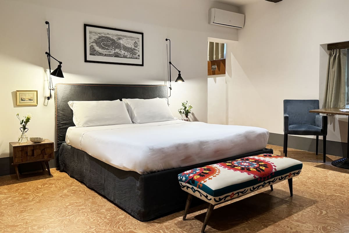 A neatly arranged bedroom with a large bed, bedside tables, a desk, and a chair.