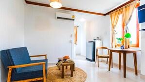 Una sala de estar con sofá, una mesita, una mesa de comedor y una zona de cocina con refrigerador.