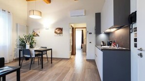 A modern kitchen with a built-in stove, a dining area with a table and chairs, and a hallway leading to another room. - Limonaia 2 | Apartment Villa Carobbi (Firenze)