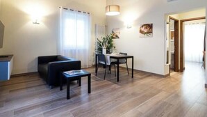 A modern living room with a sofa, coffee table, and dining area. - Limonaia 2 | Apartment Villa Carobbi (Firenze)