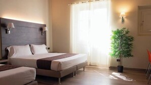 Une chambre d’hôtel avec un grand lit, deux tables de chevet, une plante en pot et une fenêtre avec des rideaux.