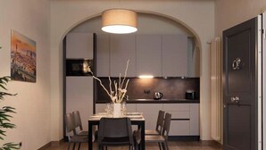 Une cuisine moderne avec un coin repas, comprenant une table dressée pour quatre personnes, un luminaire suspendu et une porte sombre.
