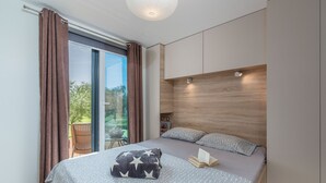 Un dormitorio moderno con una cama grande, cabecera de madera y vistas al exterior.