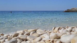 Una playa con agua cristalina y piedras.