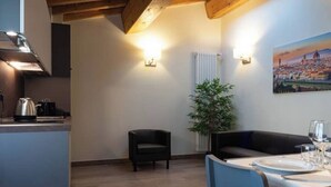 A modern kitchen with a built-in stove, a dining area with a table set for two, and a large potted plant. - Stables 4 | Apartment Villa Carobbi (Firenze)