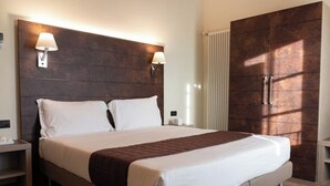 A hotel room with a large bed, two bedside lamps, a wardrobe, and a nightstand. - Stables 4 | Apartment Villa Carobbi (Firenze)