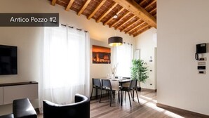 Un salon moderne avec un plafond en bois, un coin repas comprenant une table et des chaises, et un téléviseur fixé au mur.