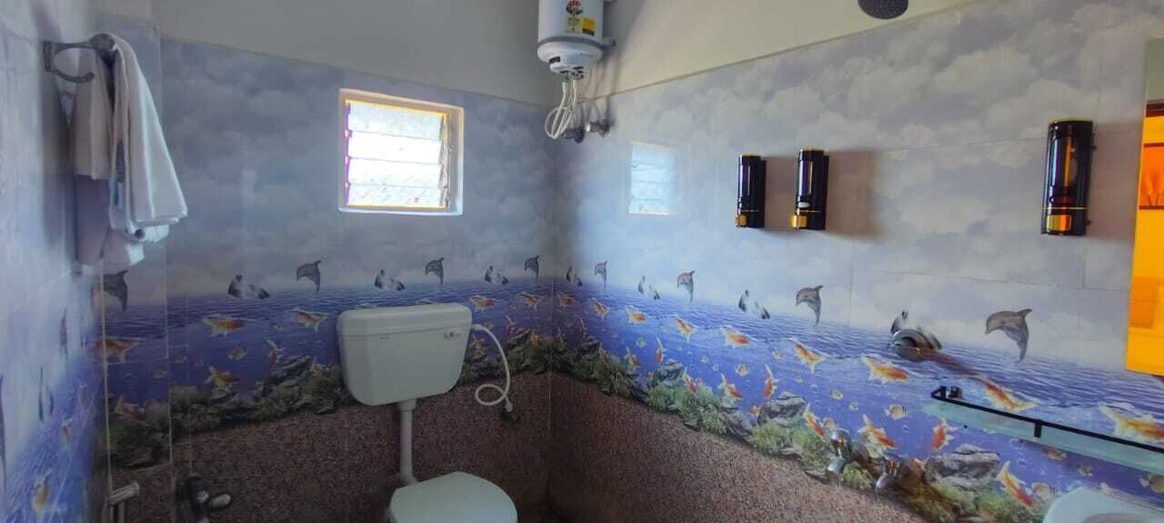 A bathroom with a marine-themed wall mural, a toilet, a window, and wall-mounted lights.