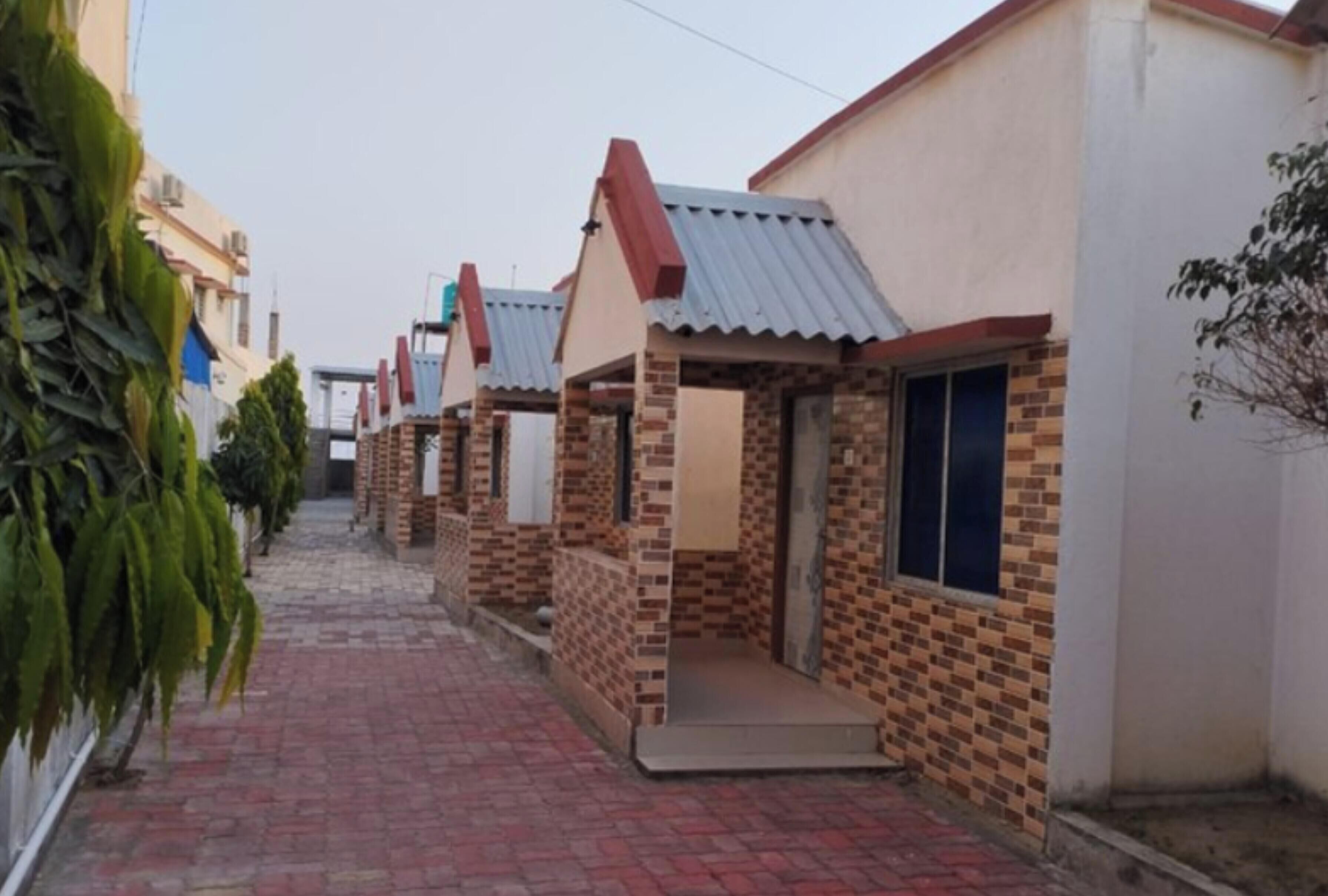 A narrow brick pathway leading to a row of small, single-story houses with tiled roofs and brick walls.