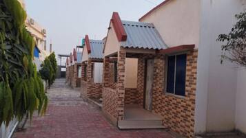 A narrow brick pathway leading to a row of small, single-story houses with tiled roofs and brick walls.