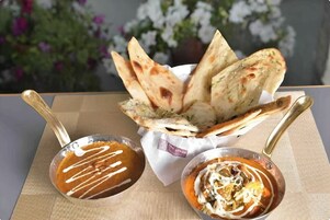 A table with a bowl of curry and naan bread.